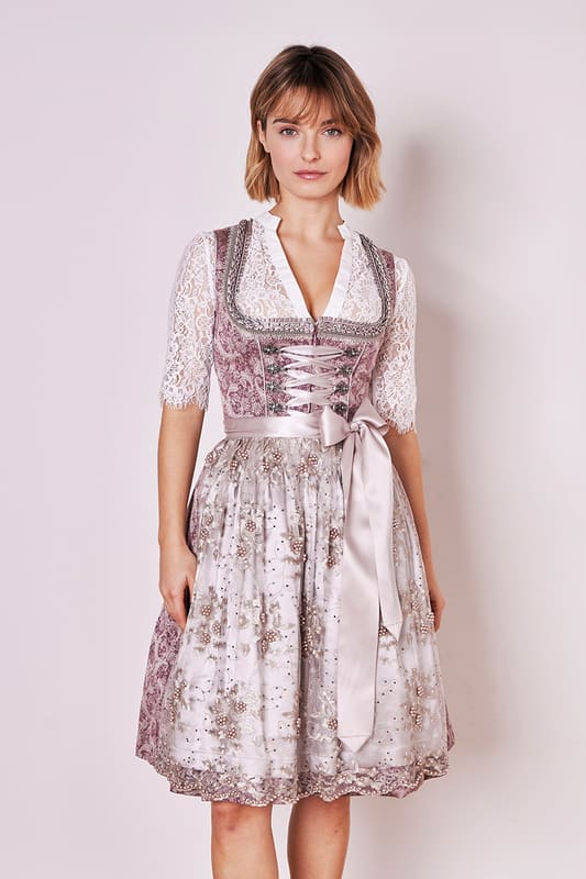 Das Dirndl Stine aus der MADL Kollektion ist ein moderner Hingucker für jede Trachtenliebhaberin. Sein ornamentales Muster und der taillierte Schnitt betonen deine Figur auf zauberhafte Weise. Der Rock mit einer Länge von 60cm ist knielang und bietet zwei praktische Eingrifftaschen mit genügend Stauraum für deine Essentials. Ein Reißverschluss vorne erleichtert das An- und Ausziehen. Das ärmellose Design mit geradem Ausschnitt unterstreicht deine Weiblichkeit und setzt dein Dekolleté charmant in Szene. Die aufwendig bestickte Dirndlschürze ist mit zahlreichen Perlen besetzt und rundet das Dirndl-Outfit ab. Mit diesem Dirndl stehst du garantiert im Mittelpunkt jeder Trachtenveranstaltung!