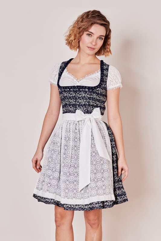 Das Dirndl Minna fällt direkt ins Auge! Das schöne Allover-Ornamentmuster harmoniert perfekt zur zarten Spitzenschürze. Es ist tailliert geschnitten