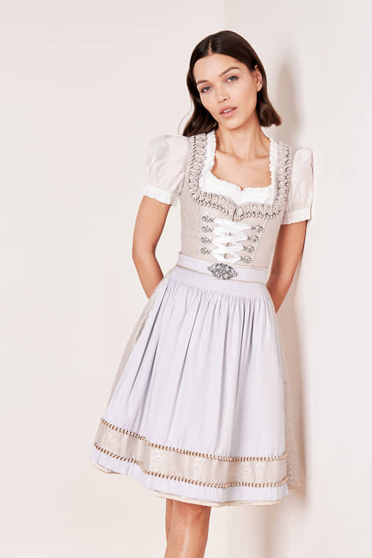 Subtile eleganz trifft auf Tradition mit unserem stilvollen Dirndl Marit. Dieses taillierte Modell überzeugt durch sein schimmerndes Muster entlang des Dirndlkleides und seinen femininen Herz-Ausschnitt. Zwei Eingrifftaschen im Rock bieten praktischen Stauraum