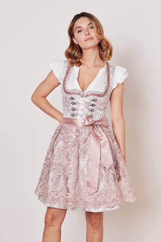 Das Dirndl Taria aus der MADL Kollektion ist ein moderner Hingucker für jede Trachtenliebhaberin. Sein ornamentales Muster und der taillierte Schnitt betonen deine Figur auf elegante Weise. Der Rock mit einer Länge von 50cm endet knapp über dem Knie und bietet zwei praktische Eingrifftaschen. Ein leichter Reißverschluss vorne erleichtert das An- und Ausziehen. Das ärmellose Design mit Herz-Ausschnitt unterstreicht deine Weiblichkeit. Die bestickte Schürze rundet das Gesamtbild ab und die Miederschnürung setzt einen zusätzlichen Akzent. Mit diesem Dirndl stehst du garantiert im Mittelpunkt jeder Trachtenveranstaltung.